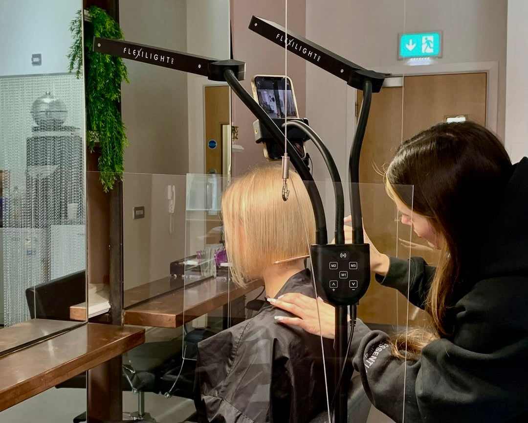 Person getting a haircut with a hair dryer in a salon setting