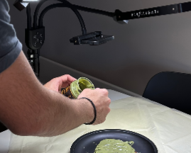 Person preparing food on a plate with a kitchen lamp in the background